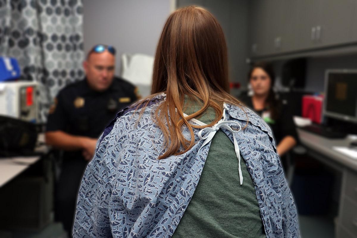 一名身份不明的性交易受害者背对着镜头，与执法人员讨论袭击后的后果